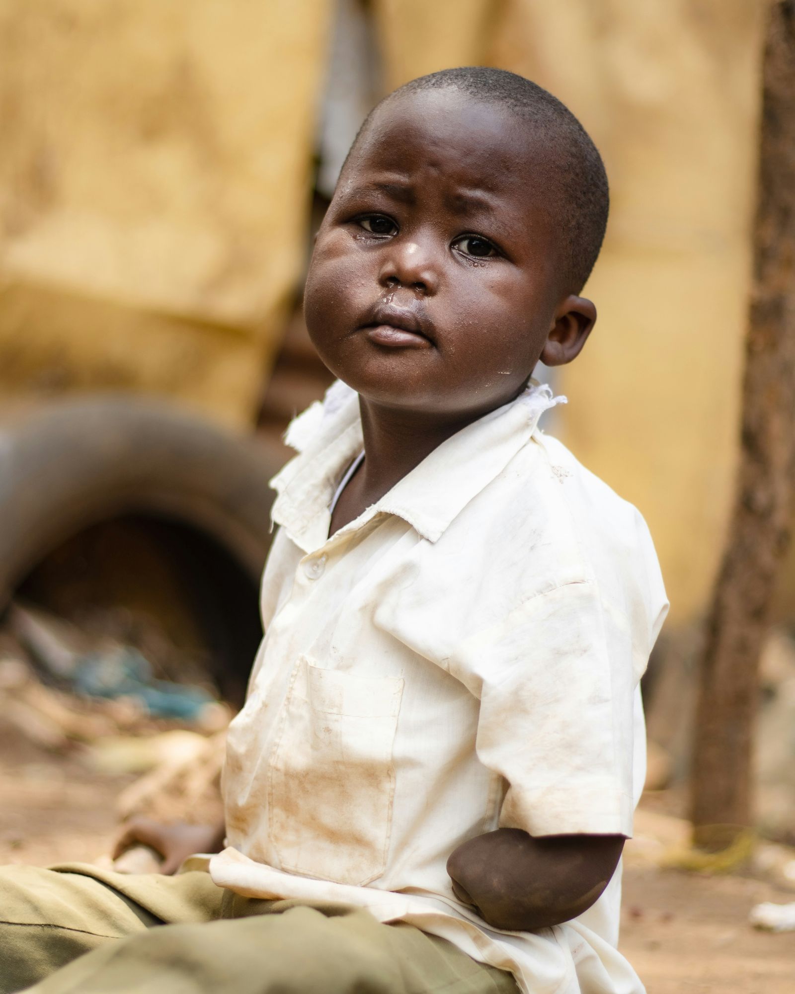 A young boy in a white shirt looking at the camera