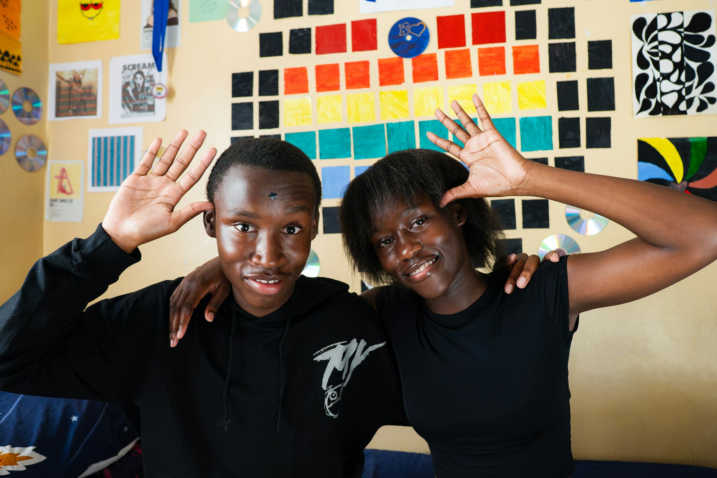 Two young people smiling and making playful gestures
